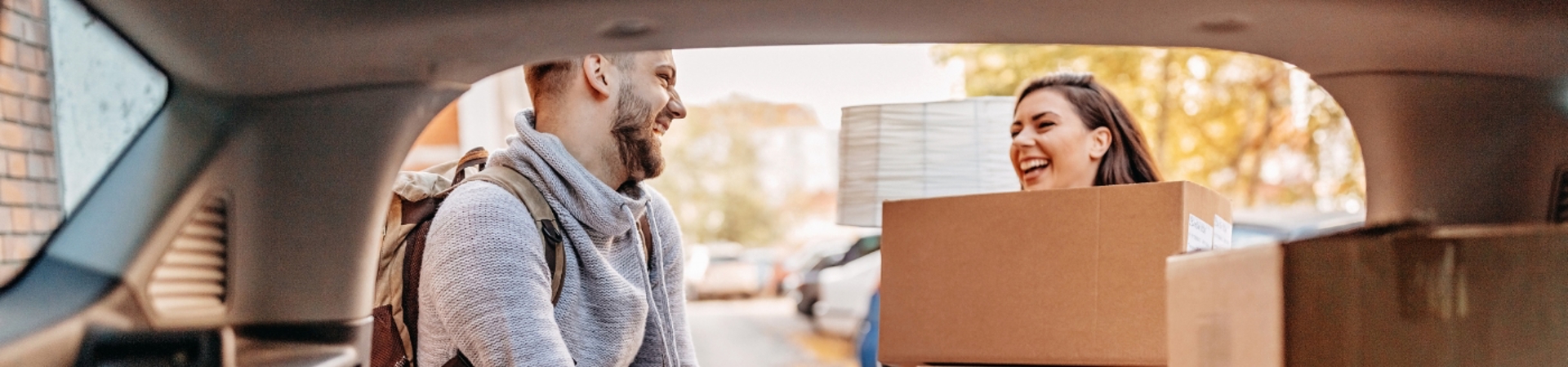 Couple taking boxes out of the back of a car